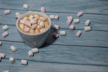 Close up of Cup hot chocolate marshmallows cacao. Cozy Coffee with marshmallows on wooden blue background. Copy space for text. Wallpaper design. Sweet unhealthy food 