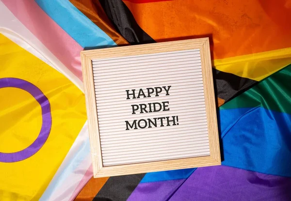 HAPPY PRIDE MONTH inscription positive quote phrase text frame on Rainbow LGBTQIA flag made from silk material. Symbol of LGBTQ pride month. Equal rights. Peace and freedom. Support LGBTQIA community