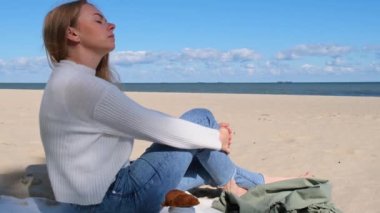 Genç bir kadın deniz kıyısında meditasyon yapıyor. Nefes almak zihinsel sağlığa iyi gelir. Nefes terapisi. Kundalini enerjisini her gün dengelemek kadın sağlığına iyi gelir.