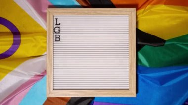 İpek malzemeden yapılmış Gökkuşağı LGBTQIA bayrağı üzerindeki LGBTQ tanımlama çerçevesini durdur. Lezbiyen, eşcinsel, iki cinsiyetli, trans, eşcinsel. LGBTQ gurur ayının sembolü. Eşit haklar. Barış ve özgürlük. Destekle