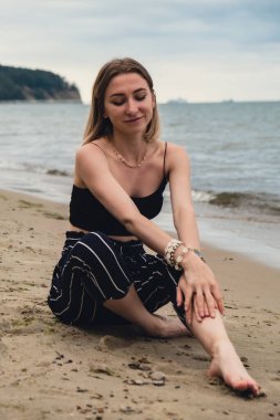 Young woman siting on blurred beachside background. Attractive female enjoying the sea shore. travel and active lifestyle concept. Springtime. Relaxation, youth, love, lifestyle solitude with nature