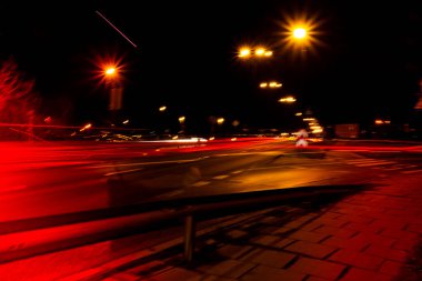 Geceleri arabaların ışıkları. Sokak lambaları. Gece Karayolu Şehri. Uzun pozlu fotoğraf gece yolu. Yoldaki renkli kırmızı ışık şeritleri. Arkaplan duvar kağıdı bulanık fotoğrafa odaklanmış