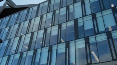 Gökyüzü arka planında cam cepheli modern ofis binası. Ofis binasının şeffaf cam duvarı. Modern Avrupa binalarının ön cephesi Ticaret Ofisi binaları