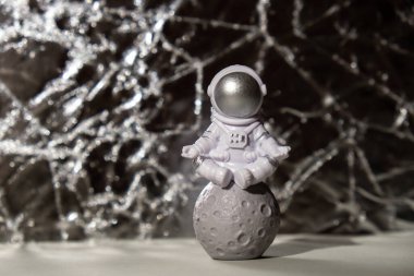 Plastic toy figure astronaut on silver background Copy space. Concept of out of earth travel, private spaceman commercial flights. Space missions and Sustainability