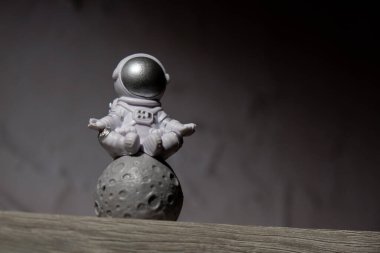 Plastic toy figure astronaut on moon concrete background Copy space. Concept of out of earth travel, private spaceman commercial flights. Space missions and Sustainability