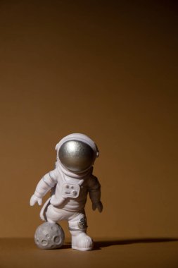 Plastic toy figure astronaut on beige neutral background Copy space. Concept of out of earth travel, private spaceman commercial flights. Space missions and Sustainability