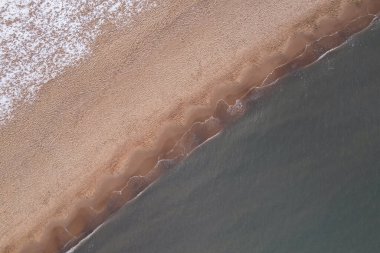 Winter in cold Baltic sea snowy beach in Gdansk. Aerial view of snow covered beach and dunes and dark calm sea nature landscape captured with drone. Winter tourism in Poland
