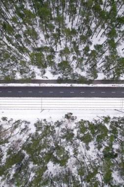 Kışın yol manzaralı, yol orman ağaçlarıyla çevrili. Kırsal kış bölgesi. Üst manzara manzarası. İHA 'dan ateş etmek. Kış ormanlarında yol karla kaplıydı. Yol gökyüzünden görünüyor.