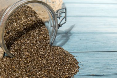 Cam kavanozda Chia tohumları. Omega 3 yağ asitleri bakımından zengin sağlıklı süper yiyecekler. Kuru, sağlıklı, doğal bileşen. Chia taneleri düşüyor. Vejetaryen yemeği. 