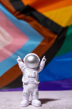 Toy astronaut on Rainbow LGBTQIA flag made from silk material background. Happy pride month. Symbol of LGBTQ pride month. Equal rights. Peace and freedom. Support LGBTQIA community. Diversity equality
