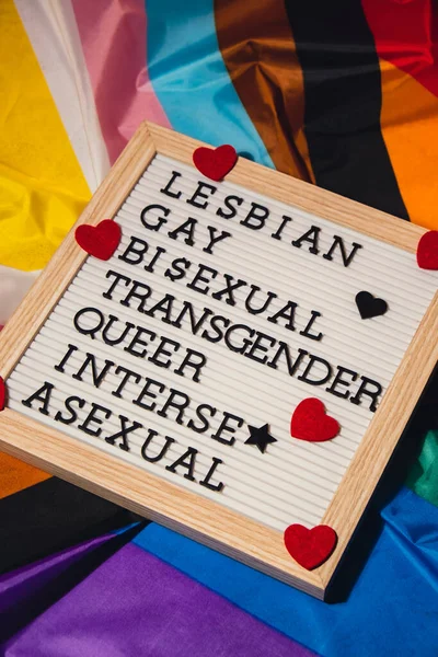 stock image LGBTQIA description frame on Rainbow LGBTQIA flag made from silk material. LESBIAN, GAY, BISEXUAL, TRANSGENDER, QUEER, INTERSEX, ASEXUAL. Symbol of LGBTQ pride month. Equal rights. Peace and freedom