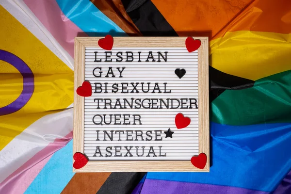 stock image LGBTQIA description frame on Rainbow LGBTQIA flag made from silk material. LESBIAN, GAY, BISEXUAL, TRANSGENDER, QUEER, INTERSEX, ASEXUAL. Symbol of LGBTQ pride month. Equal rights. Peace and freedom