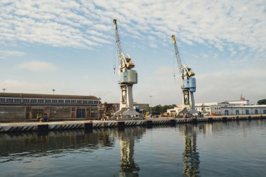 Motlawa river to Baltic Sea. Coal mine, polluting environment by the river POV from ferry swimming on river canal. Industrial building at the Gdansk Shipyard. Prefabrication workshop and heavy cranes