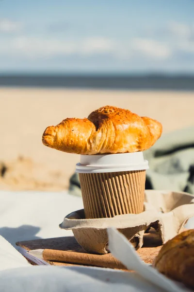 Leckere Frische Croissants Mit Kaffee Pappbecher Sandstrand Meeresküste Hintergrund Frühstück — Stockfoto