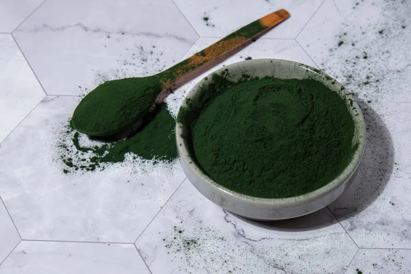 Blue-green algae Chlorella and spirulina powder in bowl with wooden spoon. Super powder. Natural supplement of algae. Detox superfood drink cocktail. Food supplement source of protein and beta