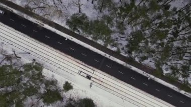 Car driving Aerial view on road in winter time, road surrounded with forest trees. Rural winter area. Top view landscape. shooting from drone. Snow covered road in winter forest. Road seen from the