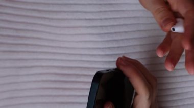 Tanımlanamayan bir kadın kablosuz kulaklık takıyor ve cep telefonu NEW PODCAST EPISODE web sitesi uygulama uygulamasını açıyor. Dikey görüntüler Ses iyileştirme, ses terapisi sağlık ritüelleri