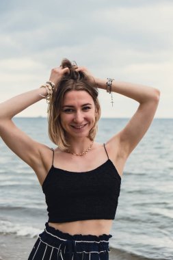 Young woman standing on blurred beachside background. Attractive female enjoying walking the sea shore. travel and active lifestyle concept. Springtime. Relaxation, youth, love, lifestyle solitude