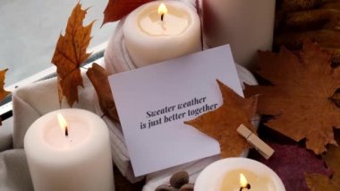 Sweater Weather, birlikte daha iyi bir tebrik kartı konseptidir. Pencere kenarındaki Hygge estetik evinde sonbahar tatilini kutlamak sonbahar yaprakları, baharatlar ve örgü örülmüş mumlar.