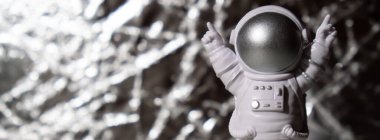 Plastic toy figure astronaut on silver background Copy space. Concept of out of earth travel, private spaceman commercial flights. Space missions and Sustainability