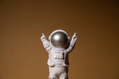 Plastic toy figure astronaut on beige neutral background Copy space. Concept of out of earth travel, private spaceman commercial flights. Space missions and Sustainability