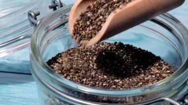 Slow motion chia seeds fall in glass jar. Healthy superfood rich in Omega 3 fatty acids. Dry healthy natural ingredient. Chia grains are falling. Vegetarian food 