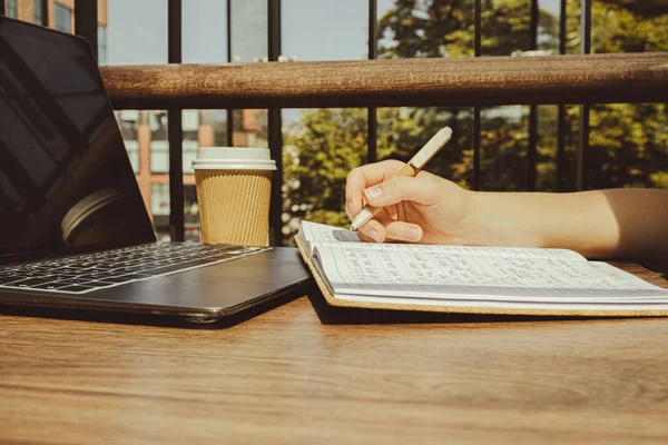 stock image Unrecognizable Young woman study at wooden table in shopping mall food court. Drinking coffee from paper cup. Student making homework Female hands writing on notebook gratitude journal self reflection