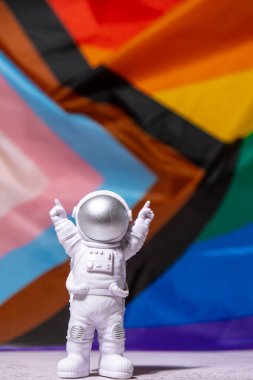 Toy astronaut on Rainbow LGBTQIA flag made from silk material background. Happy pride month. Symbol of LGBTQ pride month. Equal rights. Peace and freedom. Support LGBTQIA community. Diversity equality