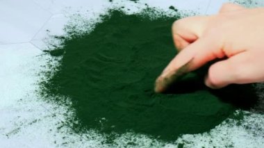 Kadın eli, mavi-yeşil yosun klorella ve spirulina tozuna kalp çizer. Süper toz. Doğal alg takviyesi. Detoks süper yiyecek içeceği kokteyli. Besin takviyesi protein ve beta