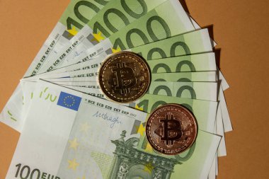 Bitcoin gold coin on bills of 100 euros eu currency. Bitcoin mining trading concept. BTC golden money. Worldwide virtual internet Cryptocurrency or crypto digital payment system. Digital coin money