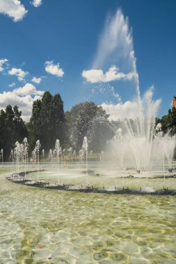Multimedia Fountain Park in Warsaw, Poland in daytime. Fountains near the royal castle in Warsaw. Fountains multimedia park in Warsaw. Sunny summer day with blue sky and green trees