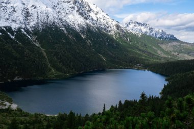 Polonya Tatry dağlarındaki Morskie Oko Karlı Dağ Kulübesi, insansız hava aracı manzarası, Zakopane, Polonya. Güzel yeşil tepelerin ve dağların kara bulutlardaki görüntüsü ve Morskie Oko Gölü 'nün yansıması.