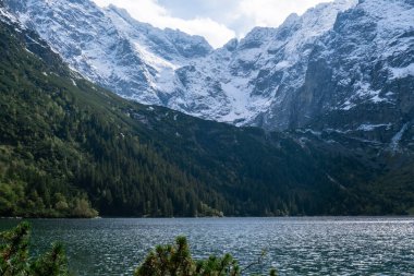 Polonya Tatry dağlarındaki Morskie Oko Gölü Karlı Dağ Kulübesi, Zakopane, Polonya. Güzel yeşil tepeler ve kara bulutlar içindeki dağlar ve Morskie Oko Gölü 'nün yansıması. Seyahat eden turist
