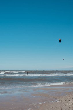 Wing Foiling uçurtmaları, rüzgar sörfü Baltık Denizi 'nde açık havada su sporu. Koyu mavi bulutlar, okyanus yüzeyinde fırtına öncesi köpük dalgaları, dramatik deniz manzarası.. 