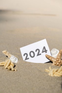 2024 yazlık metin, deniz yıldızı yaz tatili dekorunun arka planındaki kağıt tebrik kartında yeni yıl sembolü olarak başlar. Kumsalın güneş kıyısı. Tatil konsepti kartpostalı. Kaçmak Seyahat İş Konsepti