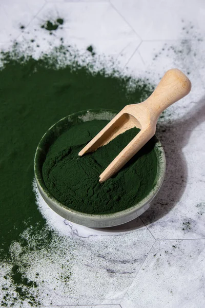 Blue-green algae Chlorella and spirulina powder in bowl with wooden spoon. Super powder. Natural supplement of algae. Detox superfood drink cocktail. Food supplement source of protein and beta