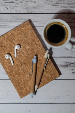 Üst manzara, bir fincan kahve, ekolojik kalem, kablosuz kulaklık ve geri dönüşüm defterli ahşap ofis masası. İş ya da öğrenci işyeri konsepti düz yatıyordu. Kişisel günlük, ses iyileştirme, akıl sağlığı