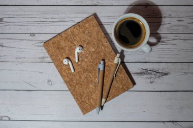 Top view, wooden Office desk with cup of coffee, eco pen, wireless headphones and recycle notebook. Business or student workspace concept Flat lay. Personal diary Audio healing, sound mental health clipart