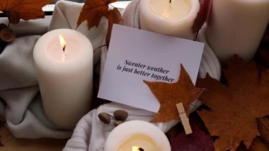 Sweater Weather, birlikte daha iyi bir tebrik kartı konseptidir. Pencere kenarındaki Hygge estetik evinde sonbahar tatilini kutlamak sonbahar yaprakları, baharatlar ve örgü örülmüş mumlar.