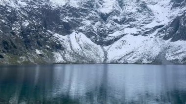 Polonya Tatry dağlarındaki Morskie Oko Karlı Dağ Kulübesi 'nin yakınındaki Kara Göl' de bulunan Çardak Staw modülü Rysamy veya Black Pond Gölü, insansız hava aracı manzarası, Zakopane, Polonya. Gökyüzü manzaralı güzel yeşil tepeler ve dağlar