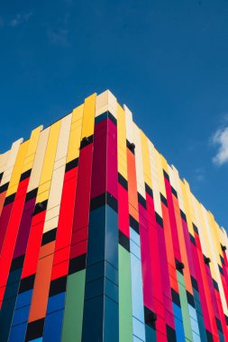 Gökyüzü arka planında cam cepheli modern renkli ofis binası. Ofis binasının şeffaf cam duvarı. Modern Avrupa binalarının ön cephesi Ticaret Ofisi binaları
