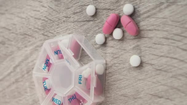 垂直ズームアウト主催者毎週のショット白いピンクの薬やカプセルと毎日服用薬の錠剤の用量で医療用薬箱の閉鎖 自宅で毎日ビタミン — ストック動画