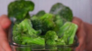 Tanımlanamayan bir kadın, dondurulmuş yemek brokolisine ev yapımı brokoli gösteriyor. Hasat konsepti. Kış için sebze depolamak sağlıklı yiyecekler, yemek malzemeleri.