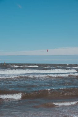 Wing Foiling uçurtmaları, rüzgar sörfü Baltık Denizi 'nde açık havada su sporu. Koyu mavi bulutlar, okyanus yüzeyinde fırtına öncesi köpük dalgaları, dramatik deniz manzarası.. 