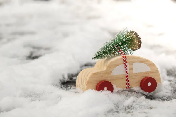 Wooden car carrying Christmas tree over snow. Copy space for text Toy car in snowy landscape. Merry Christmas and Happy New Year concept. Winter is coming Greeting card