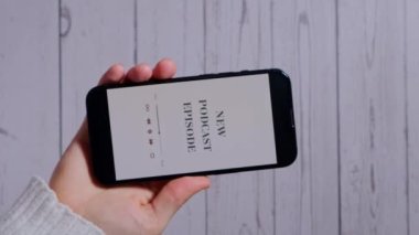Elinde cep telefonu olan tanınmayan bir kadın. YENİ PODCAST EPISODE. Kablosuz kulaklıklı web sitesi uygulaması. Dikey görüntüler Ses iyileştirme, ses terapisi sağlık ritüelleri, pozitif