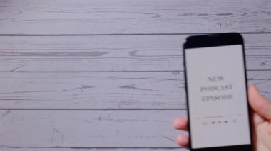 Elinde cep telefonu olan tanınmayan bir kadın. YENİ PODCAST EPISODE. Kablosuz kulaklıklı web sitesi uygulaması. Ses iyileştirme, ses terapisi sağlık ritüelleri, pozitif ruh sağlığı.
