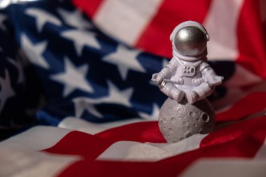 Plastic toy figure astronaut on American flag background Copy space. 50th Anniversary of USA Landing on The Moon Concept of out of earth travel, private spaceman commercial flights. Space missions and