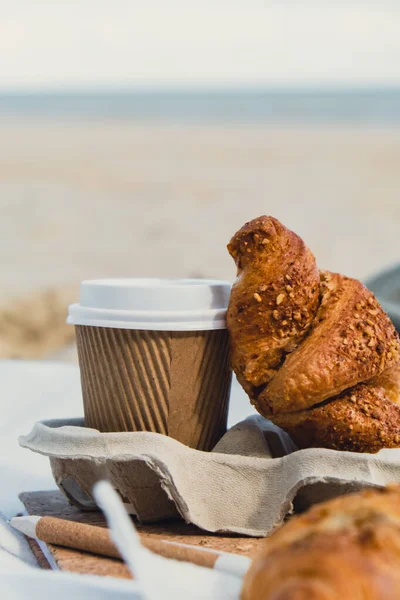 Leckere Frische Croissants Mit Kaffee Pappbecher Sandstrand Meeresküste Hintergrund Frühstück — Stockfoto