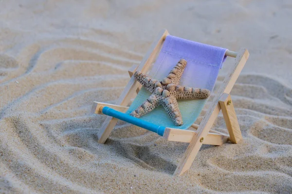 貝殻や海の星と砂のビーチのアクセサリーとビーチでの晴れた休日 サンラウンジャー海の背景に立つ 木製のビーチチェア 夏休みのコンセプト — ストック写真